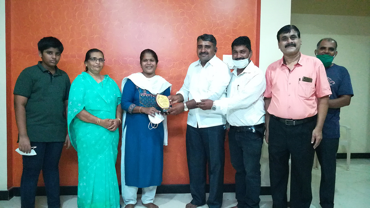 Memento being presented to Dr. Gayatri Kalyanshetty by Monish Meti committee member, and Association secretary Ganesh Lamani for her selfless service to society and humanity as a frontline warrior in the  battle against Covid-19 Pandemic and saving lives. Also seen in the photo are her family members.