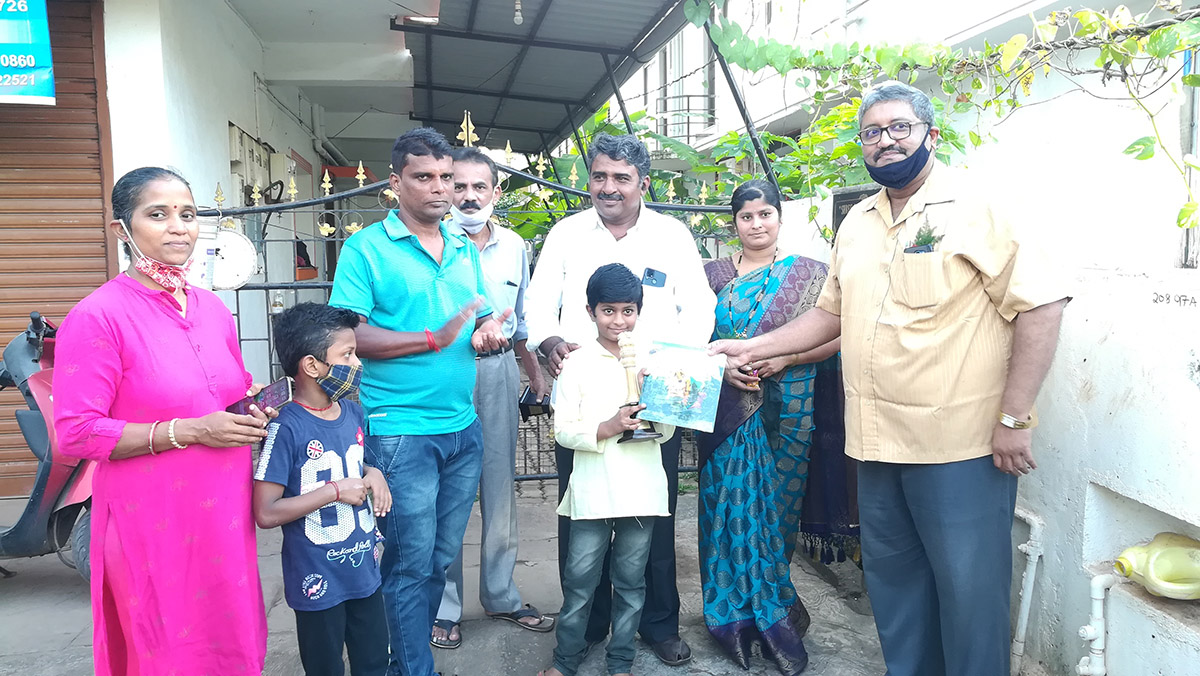 Winner of 3rd Prize awarded to Pavan Monesh Meti ( age group 4 to 7 ) for excellence in the Fancy dress competition held on 15-Aug-2021. <a href=https://youtu.be/phtqvdzLD0Y target=_blank class=blue>Competition Video</a><br><br>

Seen in the photo (from left): Smt Yadvesh Ghonge, Master Ghonge,  Shri Yadvesh Ghonge, Shri Shantaram Desai (background), Professor Shri Viraj Govind Mahatme seen presenting a set of books authored by him to Master Pavan Monesh Meti,  Shri Monesh Meti and Smt Monesh Meti (background).