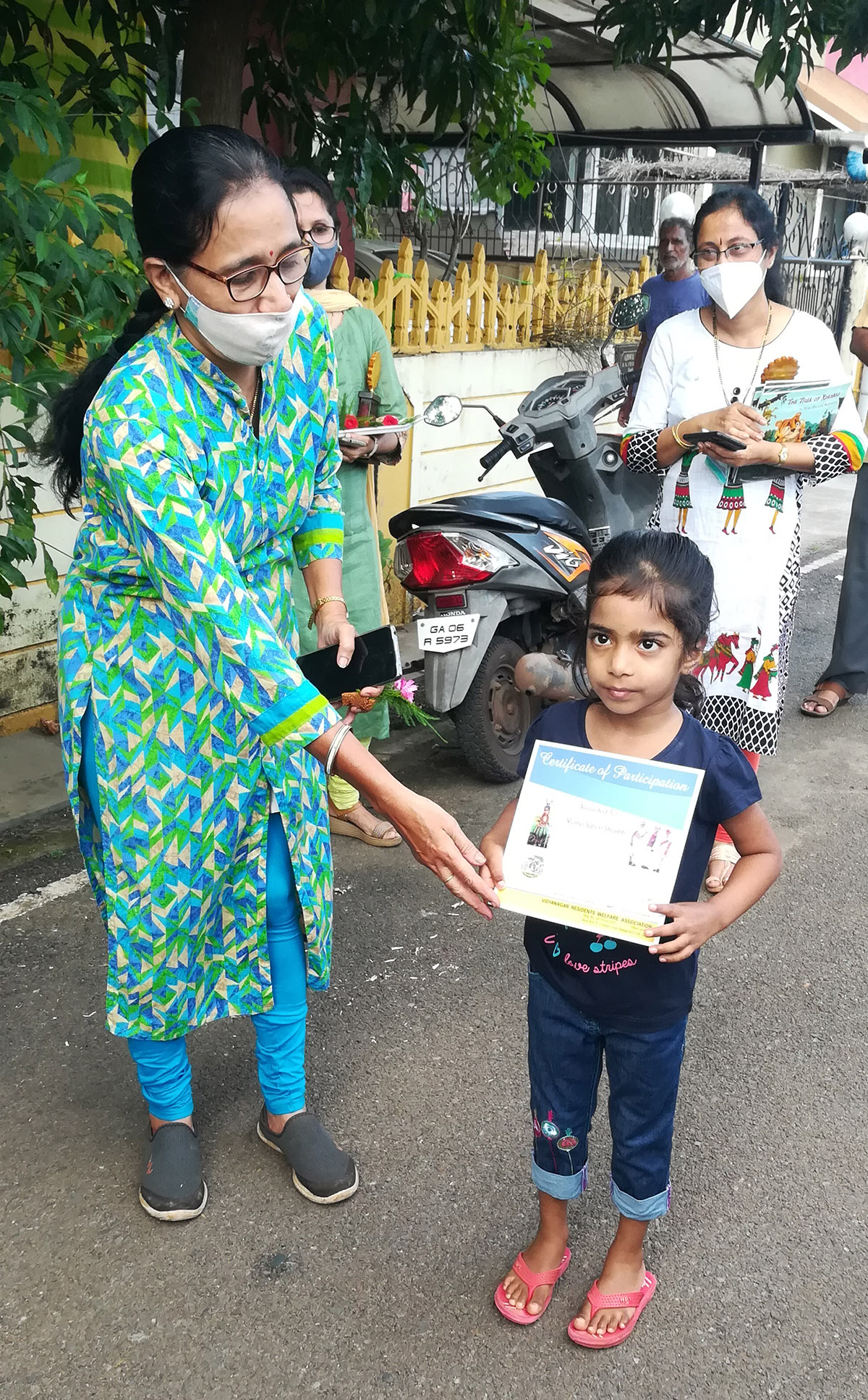 Award of participation certificate to miss Yusra Salim Shaikh for participating in the Fancy dress competition held on 15-Aug-2021. <a href=https://youtu.be/DLx0uS7wtg0 target=_blank class=blue>Competition Video</a><br><br>
Seen in the photo (from left): Smt. Shantaram Desai presenting the certificate to miss Yusra Salim Shaikh, Smt Tejal Nayak (background).