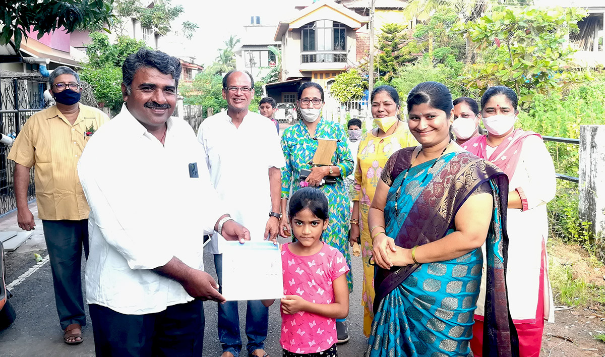 Award of participation certificate to miss Samaira Jakati for participating in the Fancy dress competition held on 15-Aug-2021. <a href=https://youtu.be/j_FD4Nt_gWg target=_blank class=blue>Competition Video</a><br><br>Seen in the photo (from left): Shri Monesh Meti presenting certificate to Samaira Jakati, Professor Shri Viraj Govind Mahatme (background), Association President Shri Santosh Desai, Smt Monesh Meti, Smt Shantaram Desai, Smt Uma Desai, Smt Luiza Correia and Smt. Vijayshri B. Gunjikar (background)