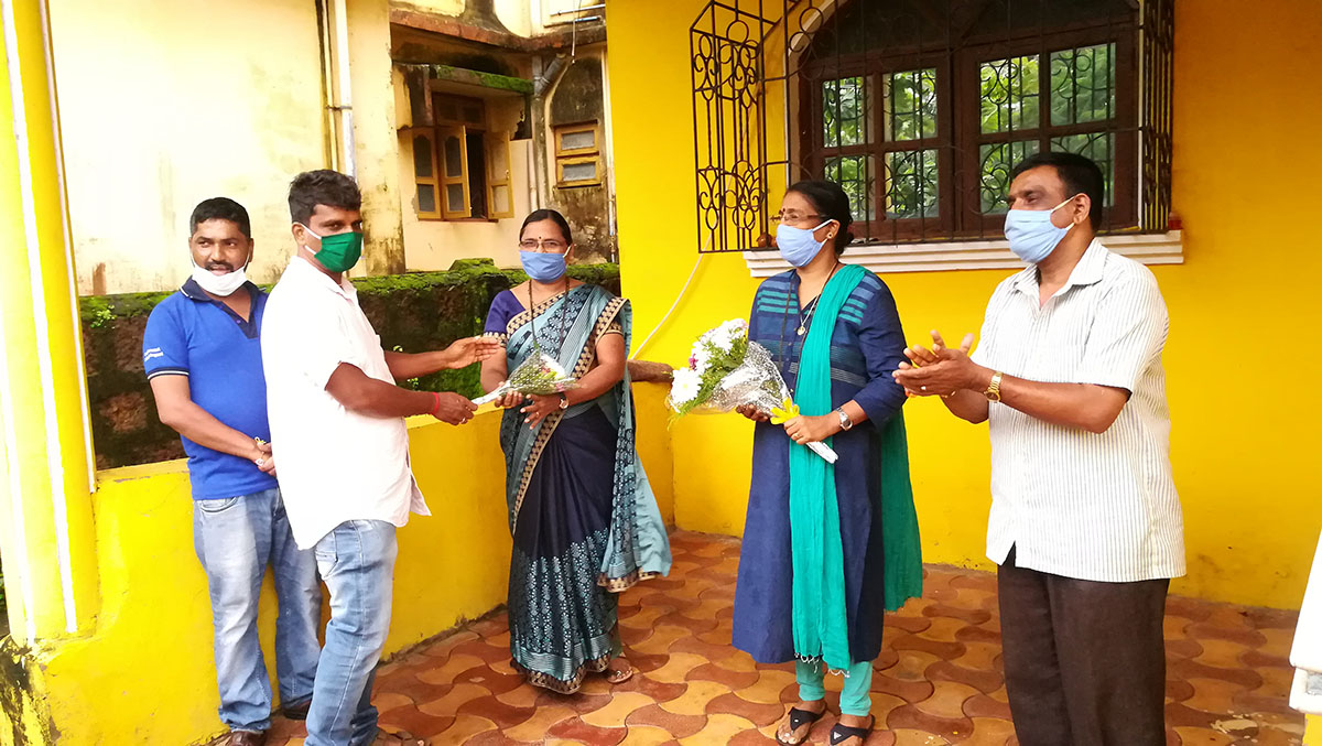 Mr. Yadvesh Gonge handing over a flower bouquet to teacher Mrs. Mandakini Kumbar  of Keshav Smruti High School in felicitation on her School securing 100% results during the 2020 SSC examination.